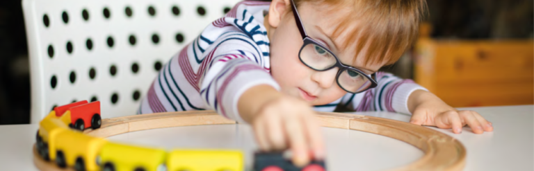 Boy playing with a wooden train track